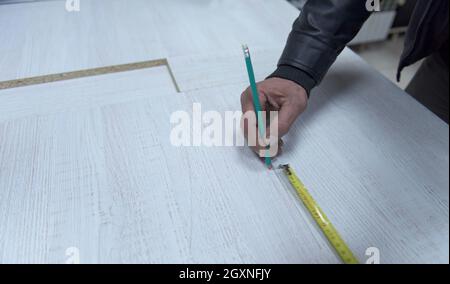 Travailleur carpenter distance de mesure pour le forage de trous dans de nouveaux meubles Banque D'Images