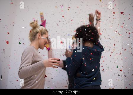 Multiethnics parti confettis jeunes heureux nouvel an fête de groupe en dansant et s'amuser à la maison Banque D'Images