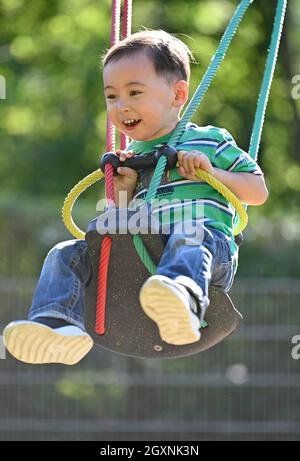 Tout-petit, 2 ans, multiethnique, eurasien, rires,Balançoires sur balançoire pour enfants, Bade-Wurtemberg, Allemagne Banque D'Images
