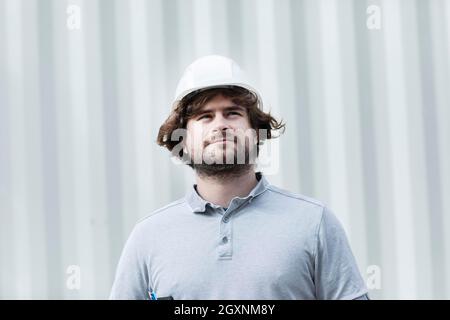 Technicien avec barbe d'âge moyen et travaillant à l'extérieur avec un polo et un casque, Freiburg, Bade-Wurtemberg, Allemagne Banque D'Images