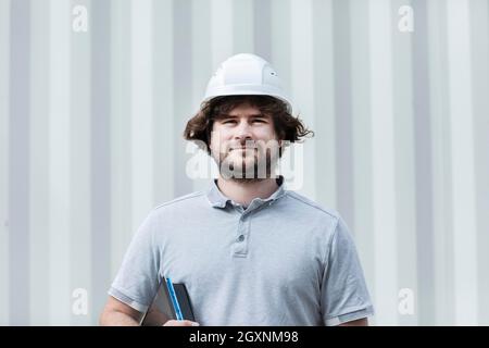 Technicien avec barbe d'âge moyen et travaillant à l'extérieur avec un polo et un casque, Freiburg, Bade-Wurtemberg, Allemagne Banque D'Images