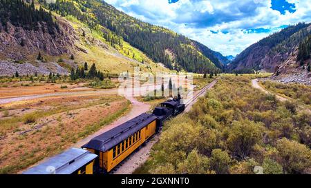 Train par vallée dans les montagnes le long de la rivière Banque D'Images