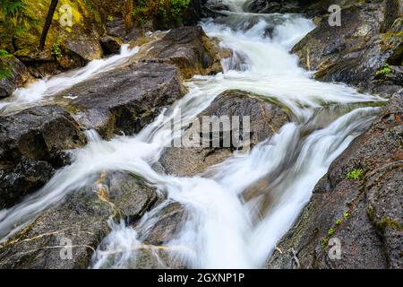 De l'eau douce dans un ruisseau qui se trouve au-dessus des rochers au ralenti à Deception Falls, dans l'État de Washington Banque D'Images