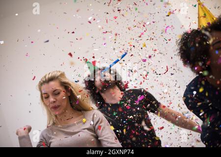 Multiethnics parti confettis jeunes heureux nouvel an fête de groupe en dansant et s'amuser à la maison Banque D'Images