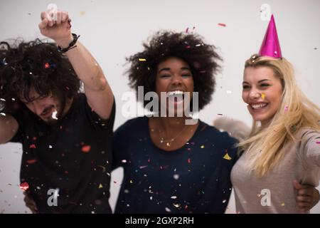 Multiethnics parti confettis jeunes heureux nouvel an fête de groupe en dansant et s'amuser à la maison Banque D'Images