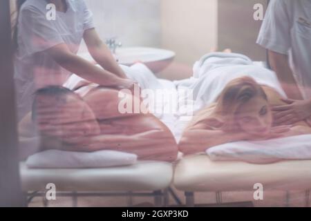 Ambiance jeune beau couple recevant un massage dos de masseur dans un spa Banque D'Images