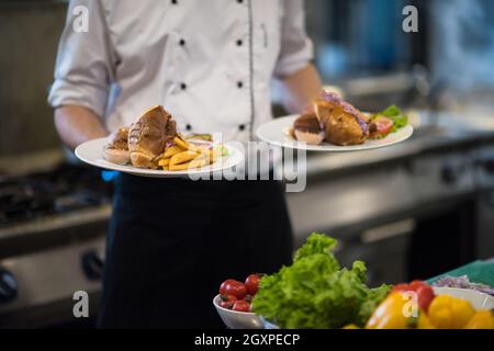 Jeune Chef presenting plats de délicieux repas dans cuisine commerciale Banque D'Images