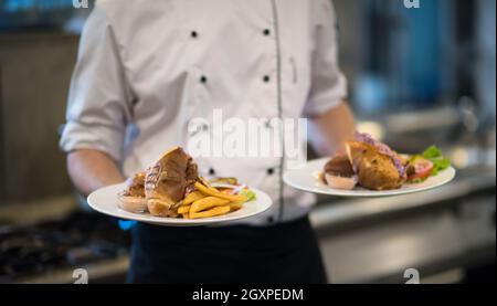 Jeune Chef presenting plats de délicieux repas dans cuisine commerciale Banque D'Images