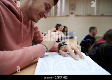 un jeune étudiant utilise une montre intelligente de tricherie dans un cours de mathématiques à l'université Banque D'Images