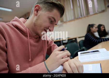 un jeune étudiant utilise une montre intelligente de tricherie dans un cours de mathématiques à l'université Banque D'Images