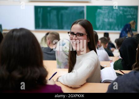 portrait d'une belle fille assise dans un amphithéâtre et parler à ses collègues pendant les cours Banque D'Images