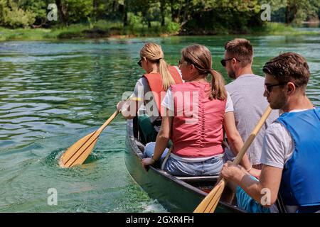 Les amis aventuriers d'un groupe explorateurs font du canoë dans une rivière sauvage entourée par la belle nature Banque D'Images