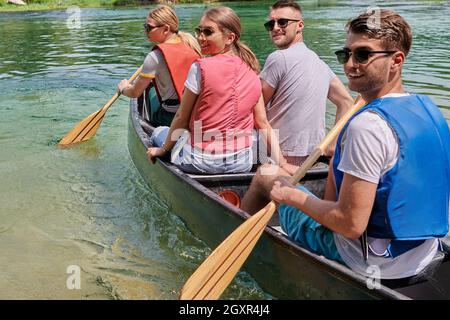 Les amis aventuriers d'un groupe explorateurs font du canoë dans une rivière sauvage entourée par la belle nature Banque D'Images