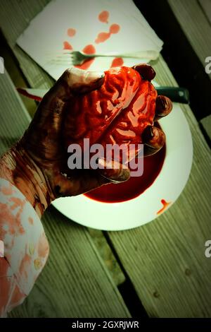 Main de zombie sanglant qui se met à manger pour le dîner avec un cerveau frais Banque D'Images