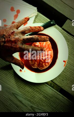 Main de zombie sanglant qui se met à manger pour le dîner avec un cerveau frais Banque D'Images