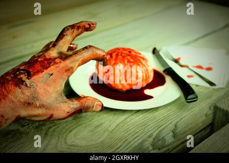 Main de zombie sanglant qui se met à manger pour le dîner avec un cerveau frais Banque D'Images