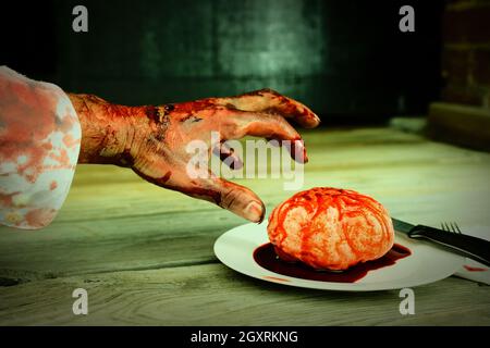 Main de zombie sanglant qui se met à manger pour le dîner avec un cerveau frais Banque D'Images