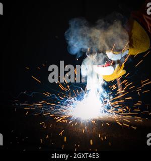 Les travailleurs de l'industrie des métaux soudeur les tôles d'acier. Eclaircir sur fond noir, gros plan. Travail intensif en usine. Banque D'Images