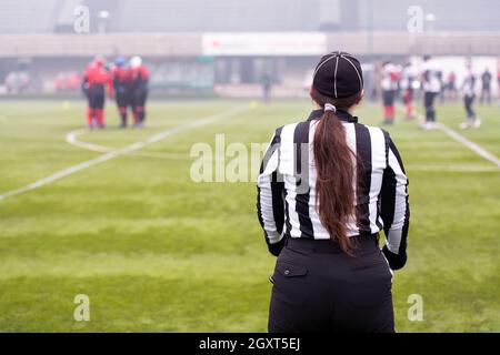 Vue arrière de l'arbitre de football américain féminin signaux donnant aux joueurs professionnels au cours de match sur le terrain du stade Banque D'Images
