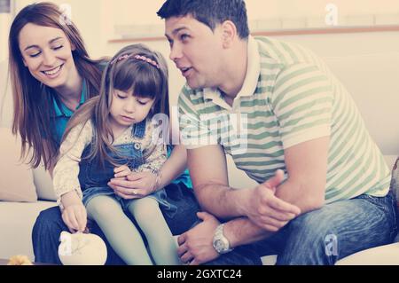 Les jeunes parrent à la maison avec de beaux enfant faire des économies et mettre des pièces en argent tirelire Banque D'Images