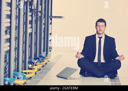 Beau jeune homme d'affaires en costume noir et cravate pratiquer cette discipline et vous détendre à network server room tout en représentant stress control concept Banque D'Images