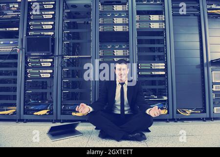 Beau jeune homme d'affaires en costume noir et cravate pratiquer cette discipline et vous détendre à network server room tout en représentant stress control concept Banque D'Images