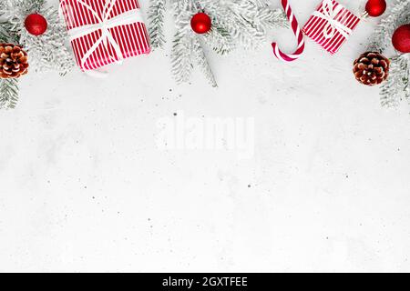 Noël, nouvel an, béton gris, plat avec cadeau rouge blanc, boîtes-cadeaux, vue de dessus. Ruban cadeau et papier d'emballage. Sapin de Noël, cônes, jouet Banque D'Images