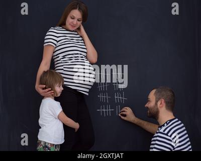 Deux jeunes femmes enceintes avec mignon comptes fille semaine de grossesse et en les écrivant à la craie sur tableau noir Banque D'Images