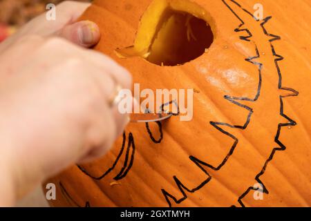 Homme sculptant la citrouille d'Halloween pour décorer les fêtes d'Halloween.Processus de fabrication de la citrouille-lanterne à la maison. Banque D'Images