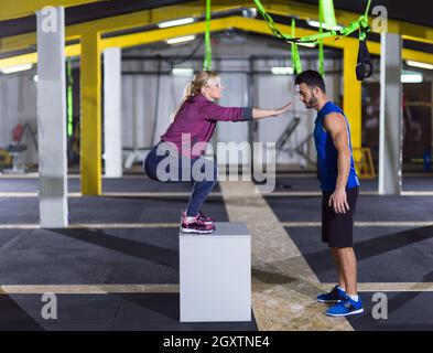 Jeune femme athlétique entraînement avec entraîneur personnel de sauter sur monter fort à crossfitness sport Banque D'Images