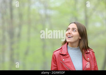 Femme émerveillement en rouge contemplant la marche dans une forêt Banque D'Images