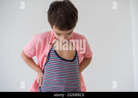 Happy little boy looking at heart love symbole dessiné sur sa poitrine isolé sur fond blanc Banque D'Images