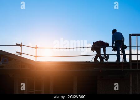 Les travailleurs de la construction d'ossature sur la toiture du bâtiment. Banque D'Images