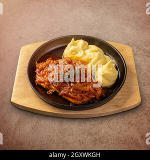 Côtelettes de porc rôties nappées de ragoût d'oignon et servies avec de la purée pommes de terre Banque D'Images