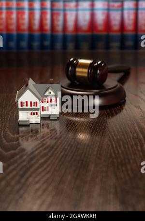 Marteau et petit modèle Maison sur table en bois avec livres de droit en arrière-plan. Banque D'Images