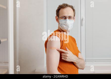 Homme caucasien senior tenant la manche de chemise pour montrer le coller le plâtre après un covid-19 jab dans l'épaule Banque D'Images