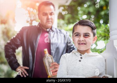 Peur et meurtri Mixed Race boy in front of Angry Man Holding bouteille d'alcool. Banque D'Images