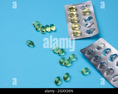 huile de poisson en capsules et blister sur fond bleu, supplément alimentaire pour la santé, gros plan Banque D'Images