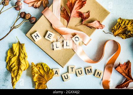 Boîte cadeau automnale attachée avec un ruban, une décoration de feuilles d'automne séchées et des mots bonjour automne Banque D'Images