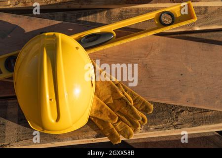 La construction du résumé de casque, gants et niveau reposant sur des planches en bois. Banque D'Images