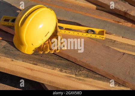 La construction du résumé de casque, gants et niveau reposant sur des planches en bois. Banque D'Images