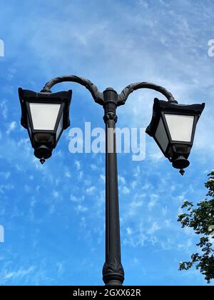 Lampe de rue sur le fond d'un arbre de printemps fleuri et d'un ciel bleu. Banque D'Images