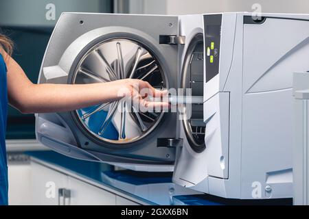 Stérilisation des instruments médicaux en autoclave. Mise au point sélective. Les assistants de dentiste sortent de la stérilisation des instruments médicaux de l'autoclave. Coin détente stérile Banque D'Images