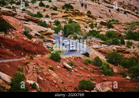 Voitures roulant sur route panoramique dans la vallée du désert de sable rouge avec falaises rocheuses Banque D'Images