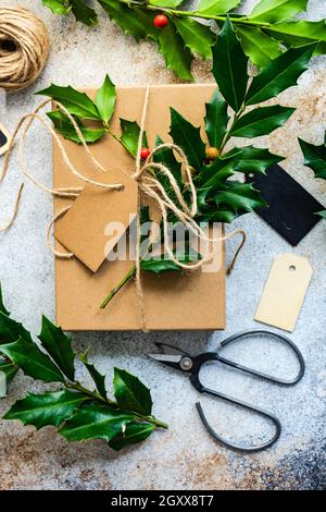 Boîte cadeau emballée décorée de houx frais pour Noël Banque D'Images