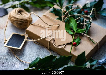 Boîte cadeau emballée décorée de houx frais pour Noël Banque D'Images