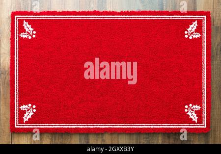 Tapis de bienvenue blanc rouge des fêtes avec coins en Holly sur fond de plancher en bois. Banque D'Images