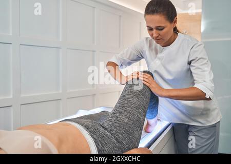 Gros plan d'une femme sérieuse massant le genou Banque D'Images