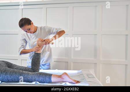 Spécialiste sérieux faisant un massage médical professionnel des pieds Banque D'Images