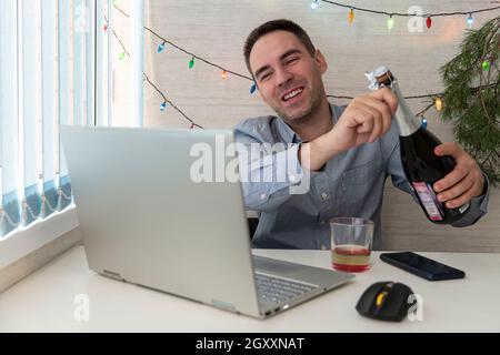 Un employé de bureau fête Noël au travail.Fêtez Noël et le nouvel an sur le lieu de travail.Un employé de bureau boit de l'alcool.Communication à distance. Banque D'Images